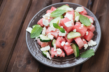 Watermelon, cucumber and cheese salad, rustic wooden background