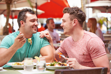 Male Couple Enjoying Lunch In Outdoor Restaurant