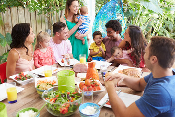 Fototapeta na wymiar Group Of Families Enjoying Outdoor Meal At Home