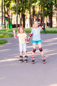 Two little girls rollerskating in the park