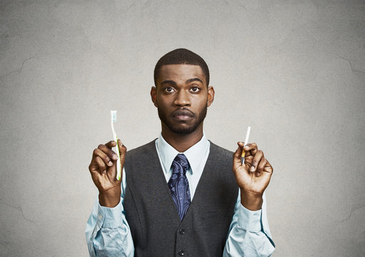 Man holds cigarette and toothbrush, bad smoker breath concept 