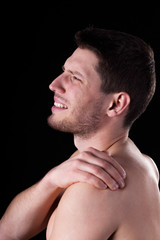 Naked man suffering from shoulder pain