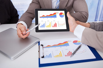 Business People Discussing Graph On Digital Tablet In Office