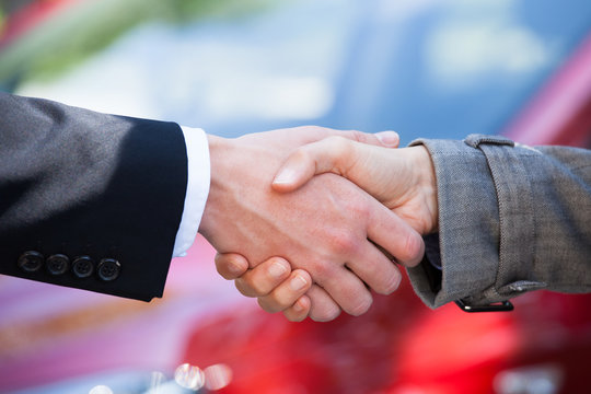 Car Dealer And Female Client Shaking Hands At Dealership