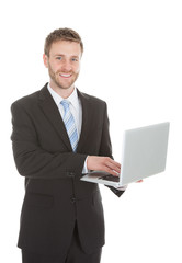 Confident Businessman Holding Laptop Over White Background