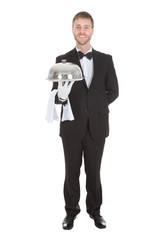 Portrait Of Confident Waiter Holding Domed Tray