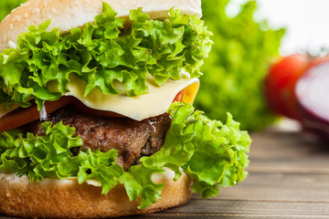 Cheeseburger with lettuce, onions and tomato in a sesame bun