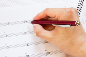 Hand with pen and music sheet