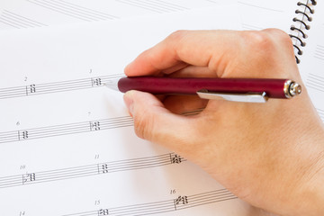 Naklejka premium Hand with pen and music sheet