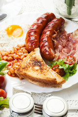 Full English breakfast with bacon, sausage, fried egg and baked