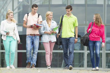 Five students walking with their school supplies