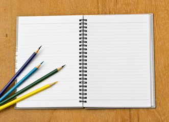 colorful pencil and notebook on wood background
