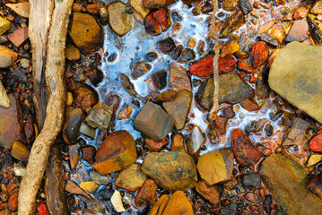 Rainbow reflection of crude oil spill on the stone at the beach