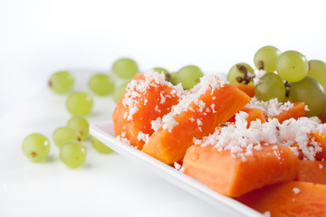sliced papaya and coconut with grapes isolated on white backgrou