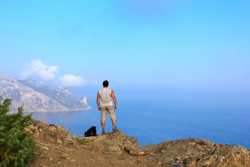 Fototapeta na wymiar Traveler looks at the beautiful seascape from the mountain top