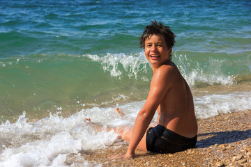 Happy young diver sitting on the sea beach