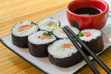 close-up of six sushi rolls with soy sauce and chopsticks