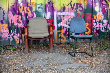 Fauteuils devant palissade de chantier avec graffitis