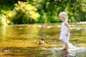 Cute toddler girl having fun by a river