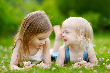 Two cute little sisters laying in the grass