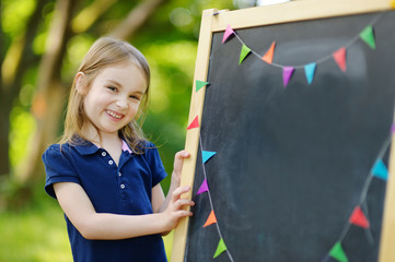 Very excited little schoolgirl by a chalkboard