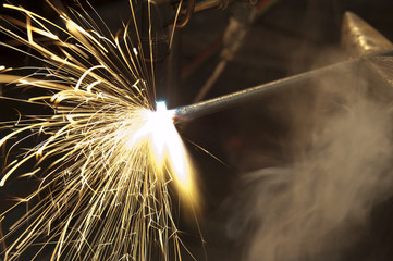 A metal fabricator utilizing a torch to heat up a piece of metal in order to shape it.