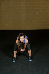 Fototapeta na wymiar A young and athletic trainer posing with a kettlebell in a gym.