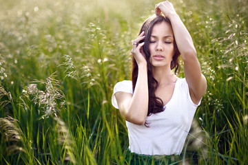 Naklejka na ściany i meble beautiful elegant brunette girl in a field