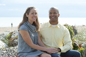 Obraz premium A young and happy interracial couple posing near the beach on a sunny day.