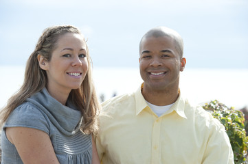 A young and happy interracial couple posing near the beach on a sunny day.