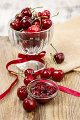Bowl of cherry jam on wooden table and fresh cherries around