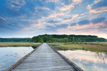 wooden path on lake water at sunrise