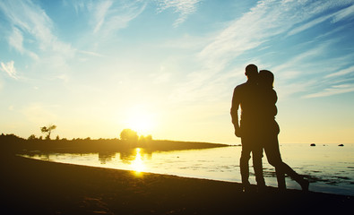 Fototapeta premium Young couple enjoying the sunset. Two silhouettes.