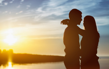 Young couple enjoying the sunset. Two silhouettes.