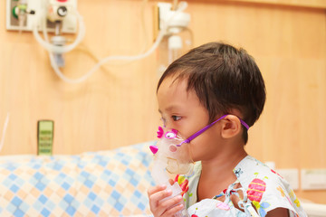 little boy lying in bed with inhalator mask