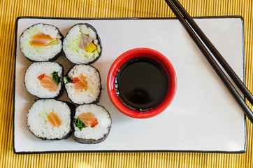 six sushi rolls with soy sauce and chopsticks