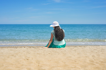 Fototapeta na wymiar Brunette female sitting alone on the beach