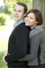 Obraz premium A happy, young and attractive couple looking at the camera on a sunny day at a park
