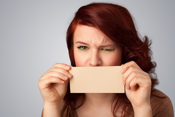 Cute girl holding white card at front of her lips with copy spac