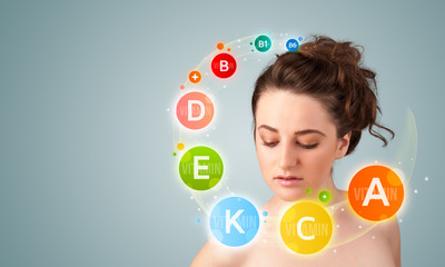 Pretty young girl with colorful vitamin icons and symbols