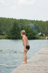 Chłopiec skaczący z pomostu do wody 