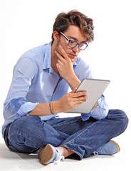 Hombre joven sentado usando un tablet digital.