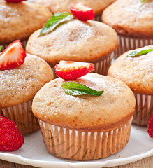 Strawberry muffin on a white plate with a fresh strawberry