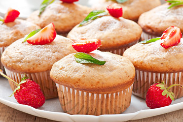 Strawberry muffin on a white plate with a fresh strawberry