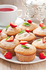 Strawberry muffin on a white plate with a fresh strawberry
