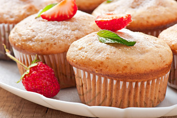 Strawberry muffin on a white plate with a fresh strawberry