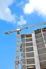 Crane and building construction site against blue sky