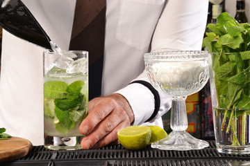 Barman preparando coctel de mohito,sirviendo hielo.