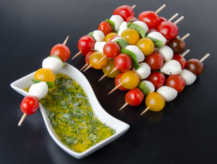 Cherry tomatoes and mozzarella on skewers and a vinaigrette sauc