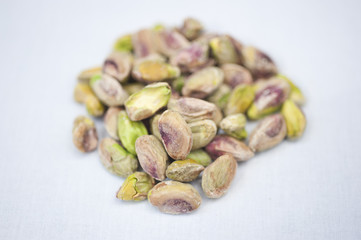 A heap of pistachio nuts on a white background on a sunny day.